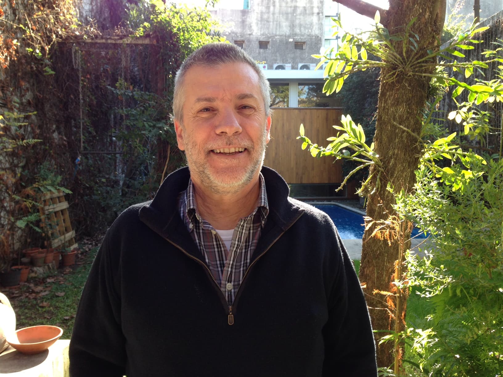 Retrato de José Luis Díaz sonriendo, en un jardín soleado.